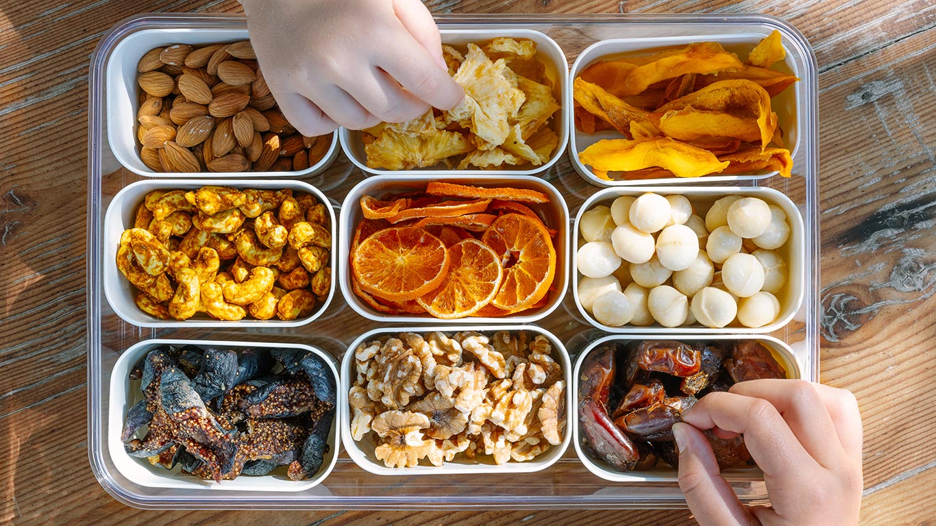 Assorted snacks in a compartmentalized tray on a wooden surface