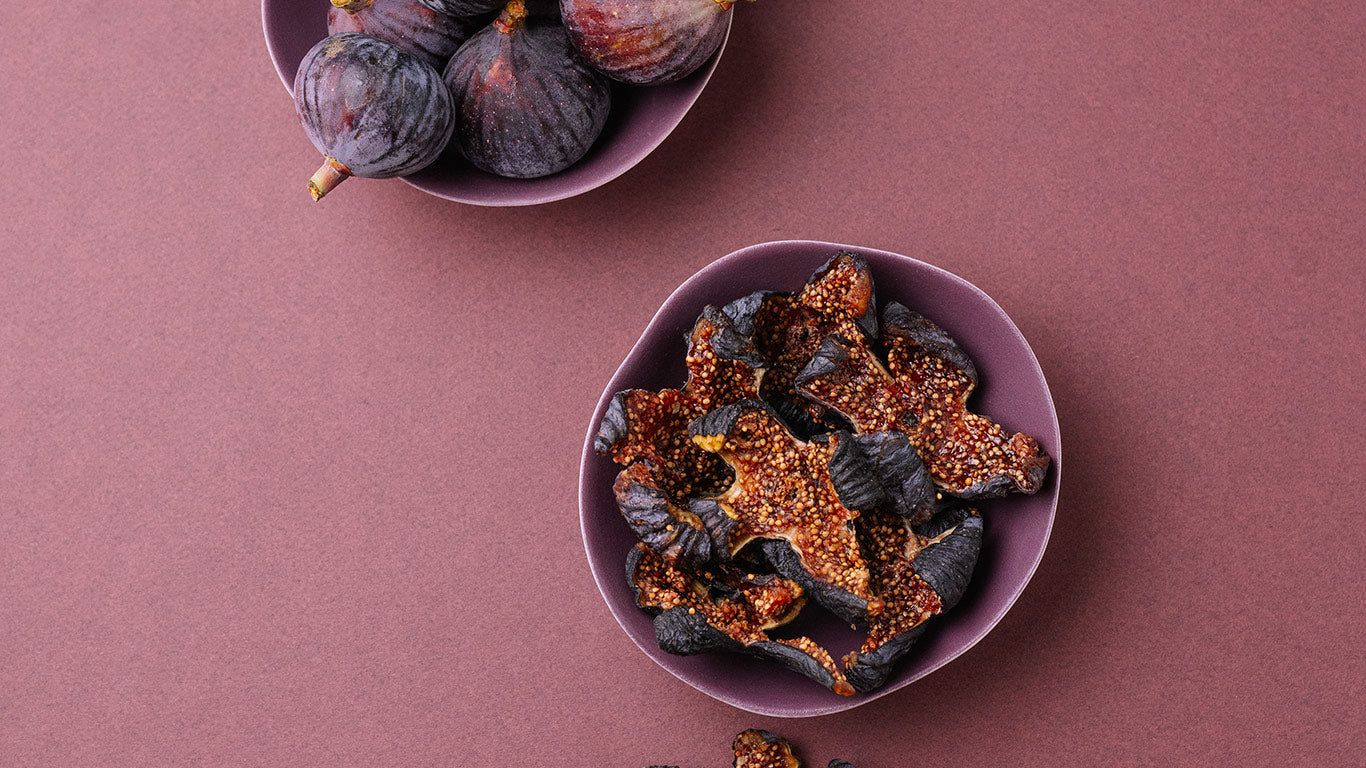 Two bowls of dried figs on a pinkish-brown background